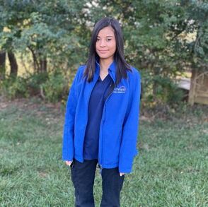 Girl staff member standing and smiling wearing blue Eastview Animal Hospital coat